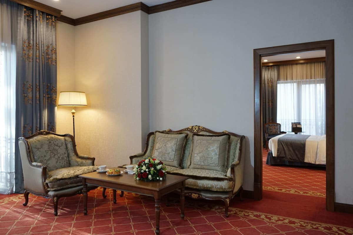 Een hotelkamer met een bank, fauteuil en een tafel met bloemen.