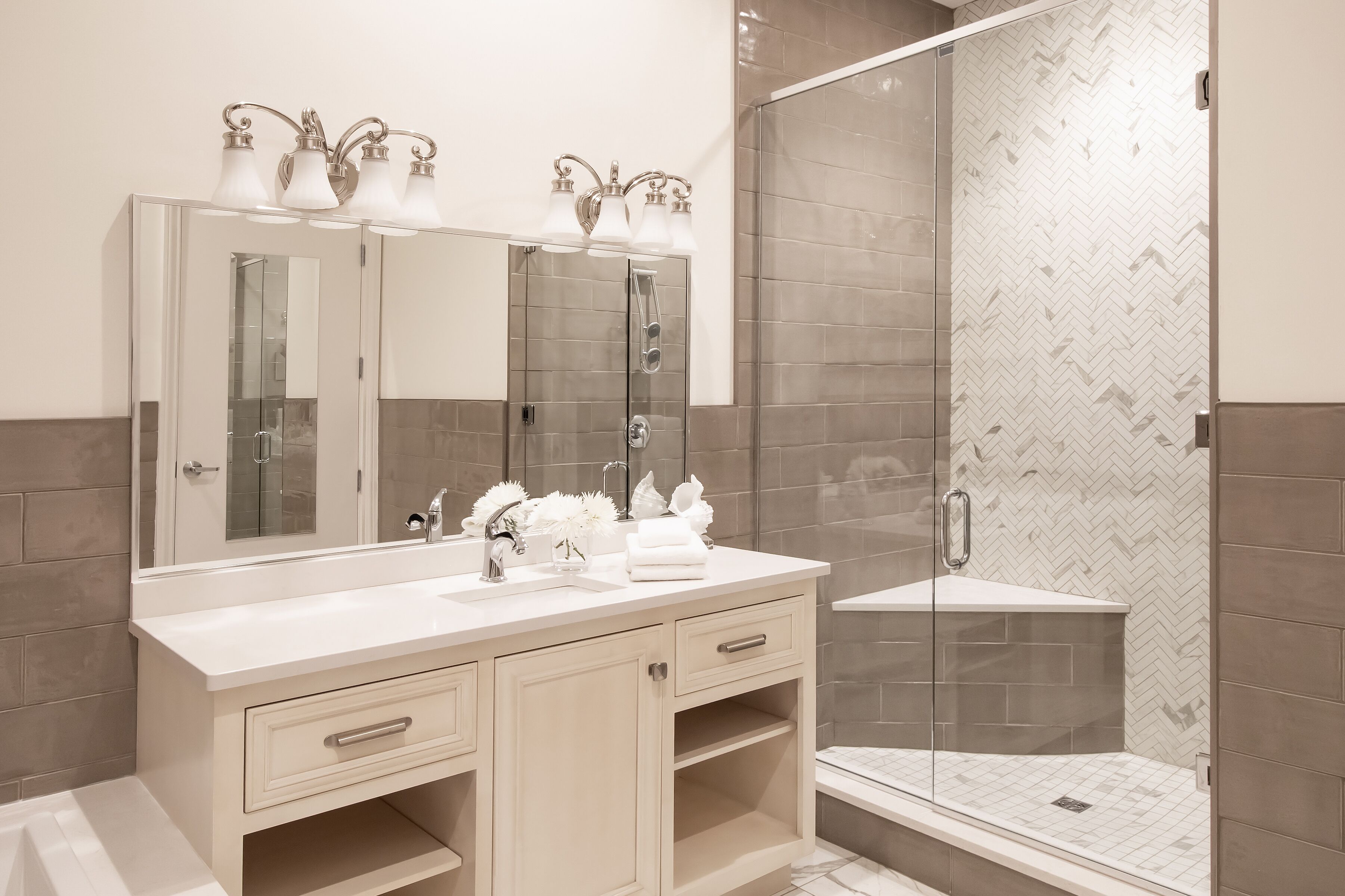 Een moderne badkamer met een dubbele wastafel, een grote spiegel en een douche met glazen wanden.
