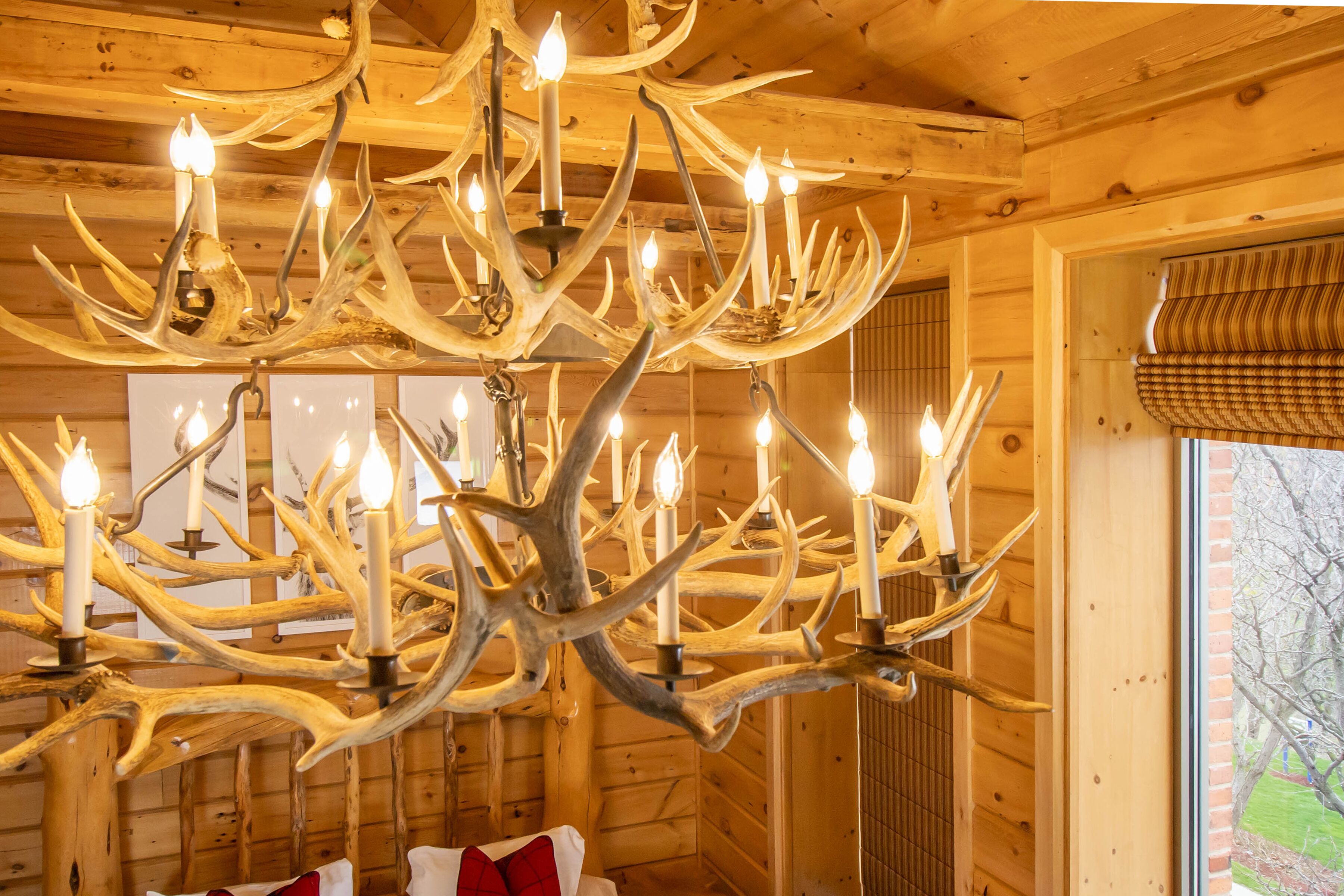 Un lustre fait de bois de cerf dans une cabane en bois avec une fenêtre.