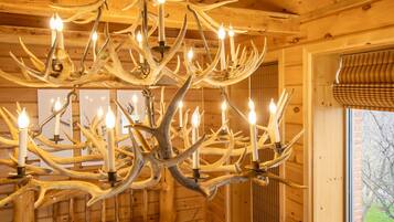 Un lustre fait de bois de cerf dans une cabane en bois avec une fenêtre.