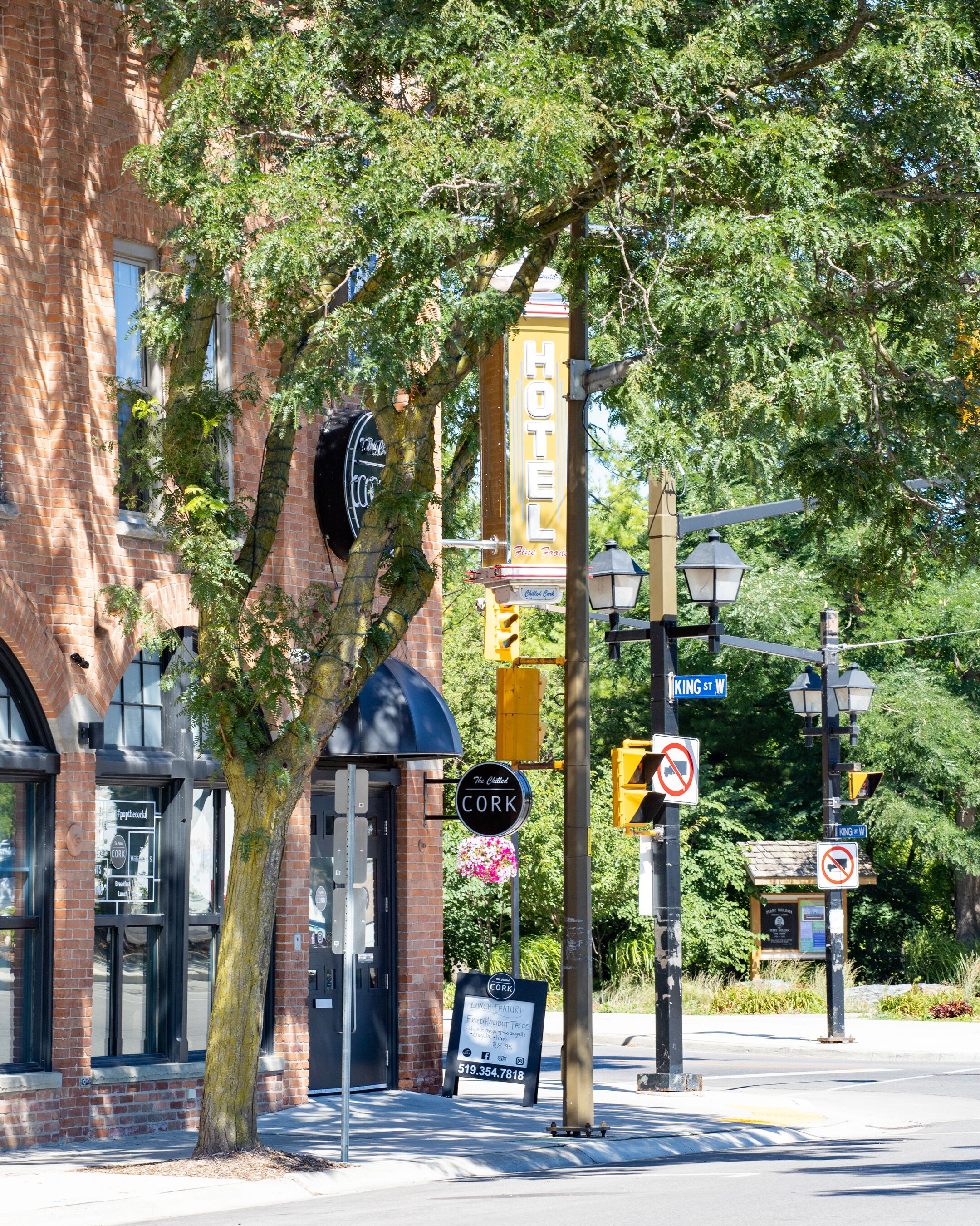 Un hotel con un letrero llamativo, un árbol frente a él y una señal de calle que indica 'King St W'.