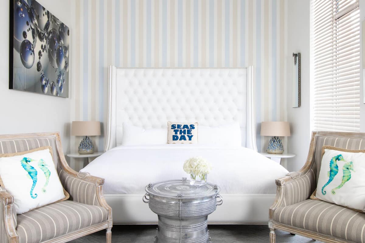 A hotel room with a large bed, two armchairs, a small round table, and a decorative pillow.