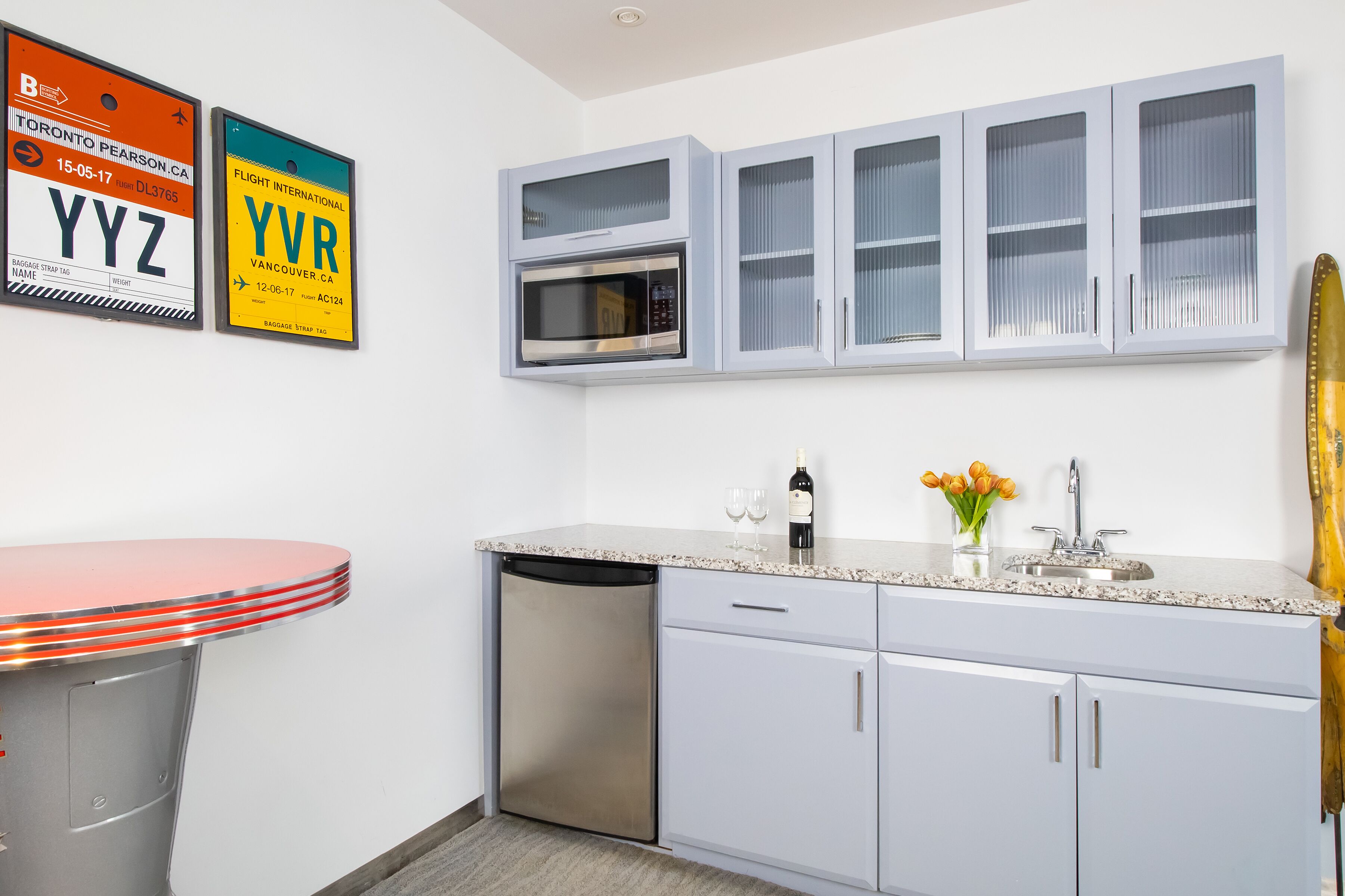A kitchen with a microwave, a dishwasher, and a sink. There are two framed license plates on the wall.