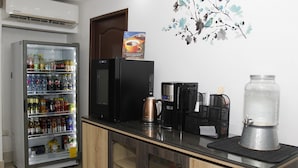 Una kitchenette con un refrigerador lleno de bebidas, una cafetera y un dispensador de agua.