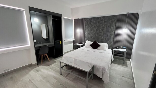 Una habitación de hotel moderna con cama, mesita de noche y escritorio con silla.
