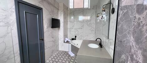 Un baño moderno con puerta oscura, bañera, lavabo y espejo.