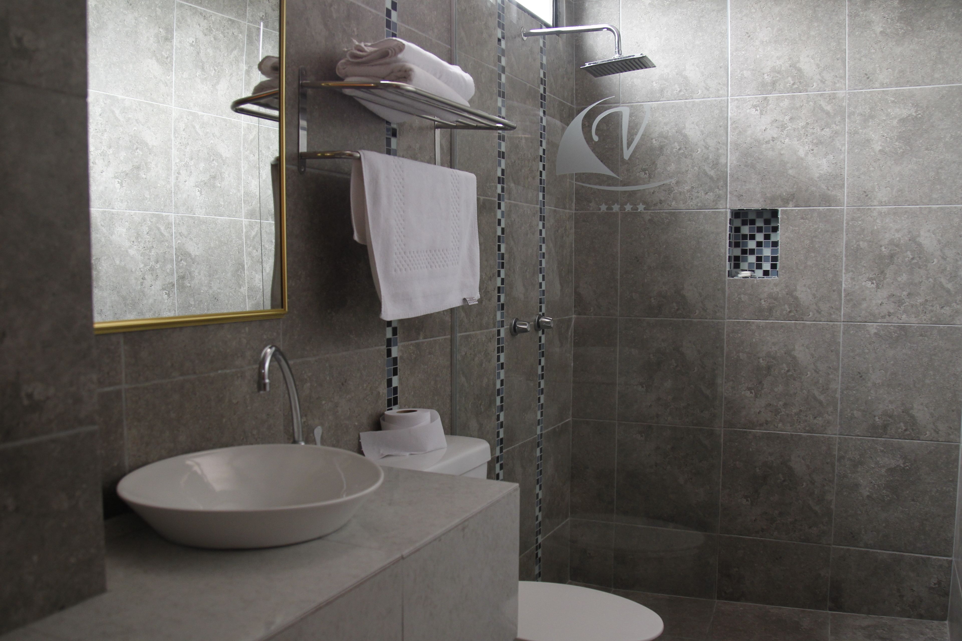 Een moderne badkamer met een grote spiegel, een wastafel, toilet en douche.
