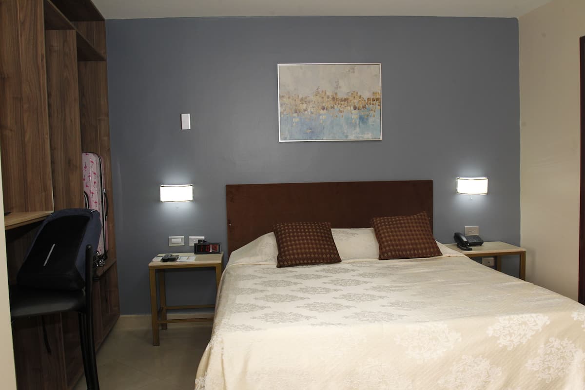 Une chambre d’hôtel comprenant un lit, deux tables de chevet, un bureau et une chaise.