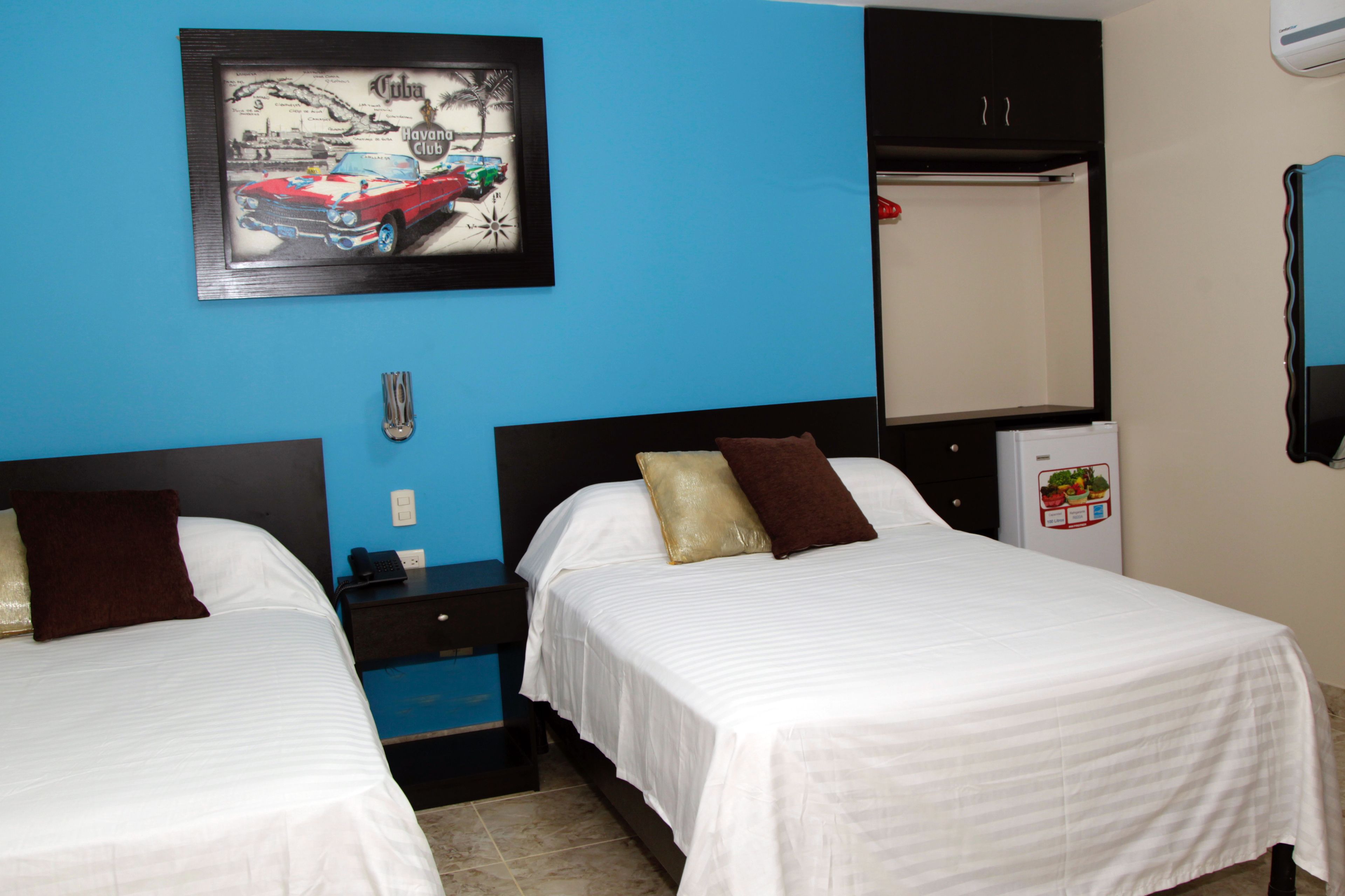 Een hotelkamer met twee bedden, een nachtkastje, een kledingkast en een koelkast.