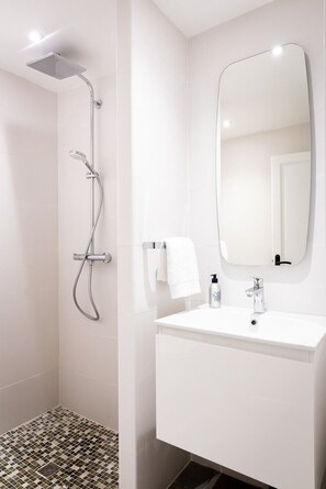 Un baño moderno con ducha, lavamanos y espejo.
