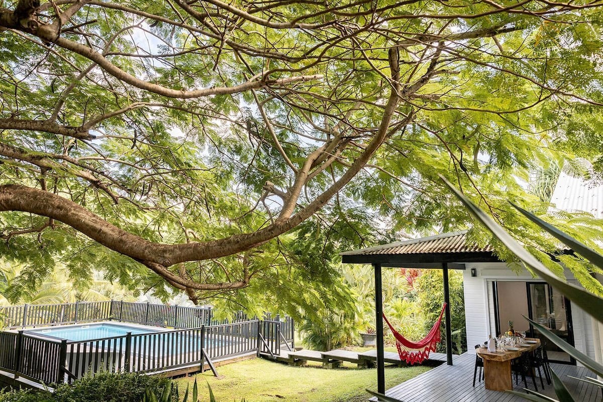 Un patio trasero con piscina, una hamaca y un área de patio techada.