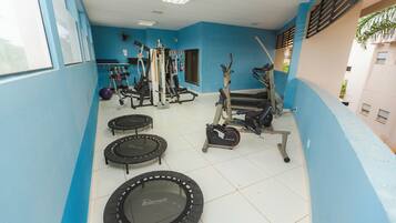 Un gimnasio con equipo de ejercicio, incluyendo cintas de correr, una bicicleta estática y una cama elástica.