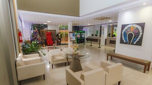 A lobby with a Christmas tree, seating area, and a reception desk. - Hotel Marina - Oficial (Caldas Novas)