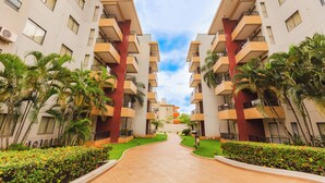 A modern apartment complex with a central walkway, balconies, and lush greenery. - Hotel Marina - Oficial (Caldas Novas)