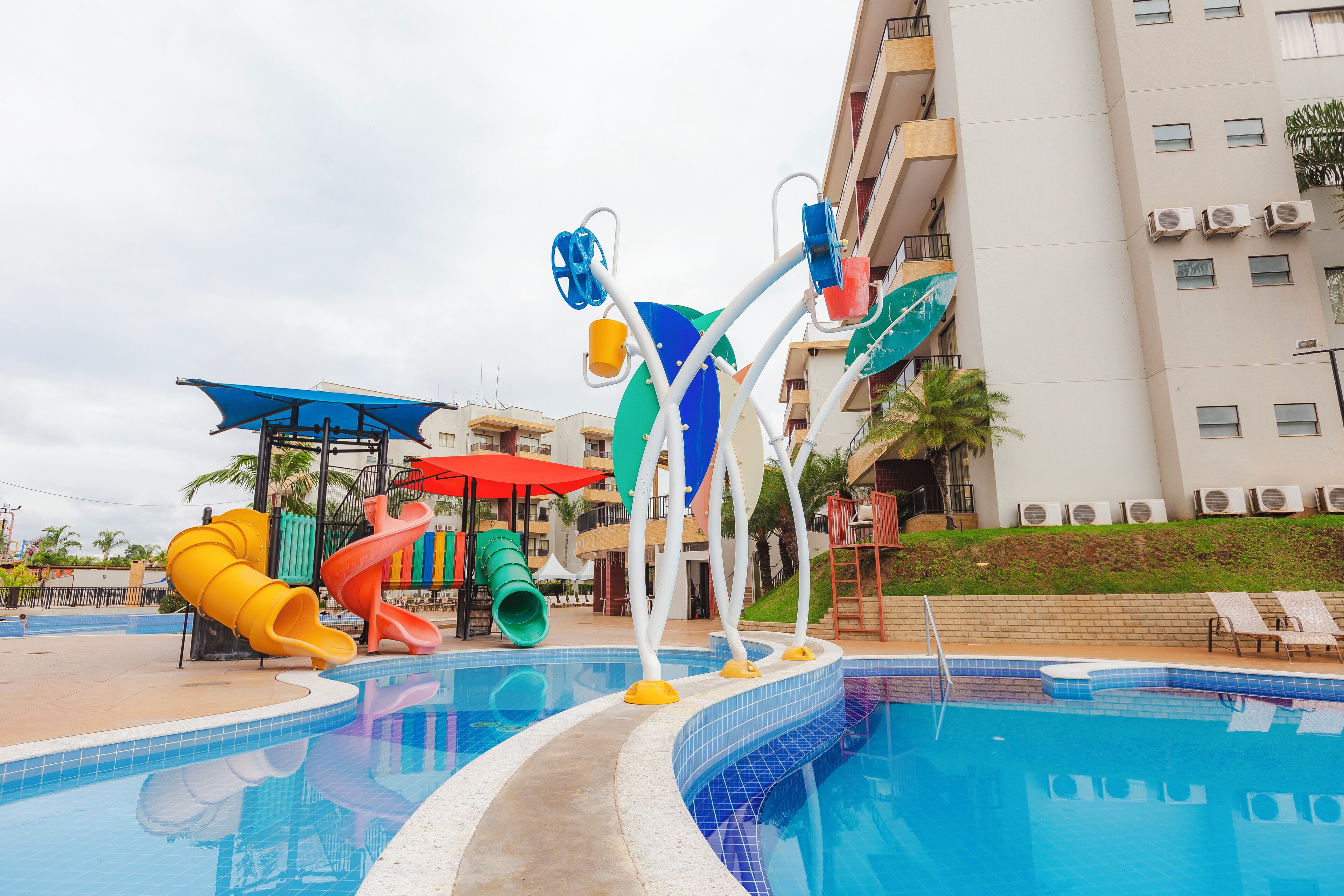 A swimming pool with colorful slides and a water play area.