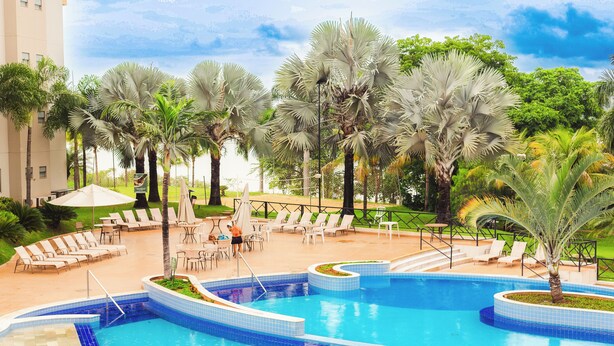 A pool area with multiple swimming pools, lounge chairs, and palm trees. - Hotel Marina - Oficial (Caldas Novas)