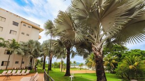 A hotel courtyard with palm trees, lounge chairs, and a pool. - Hotel Marina - Oficial (Caldas Novas)