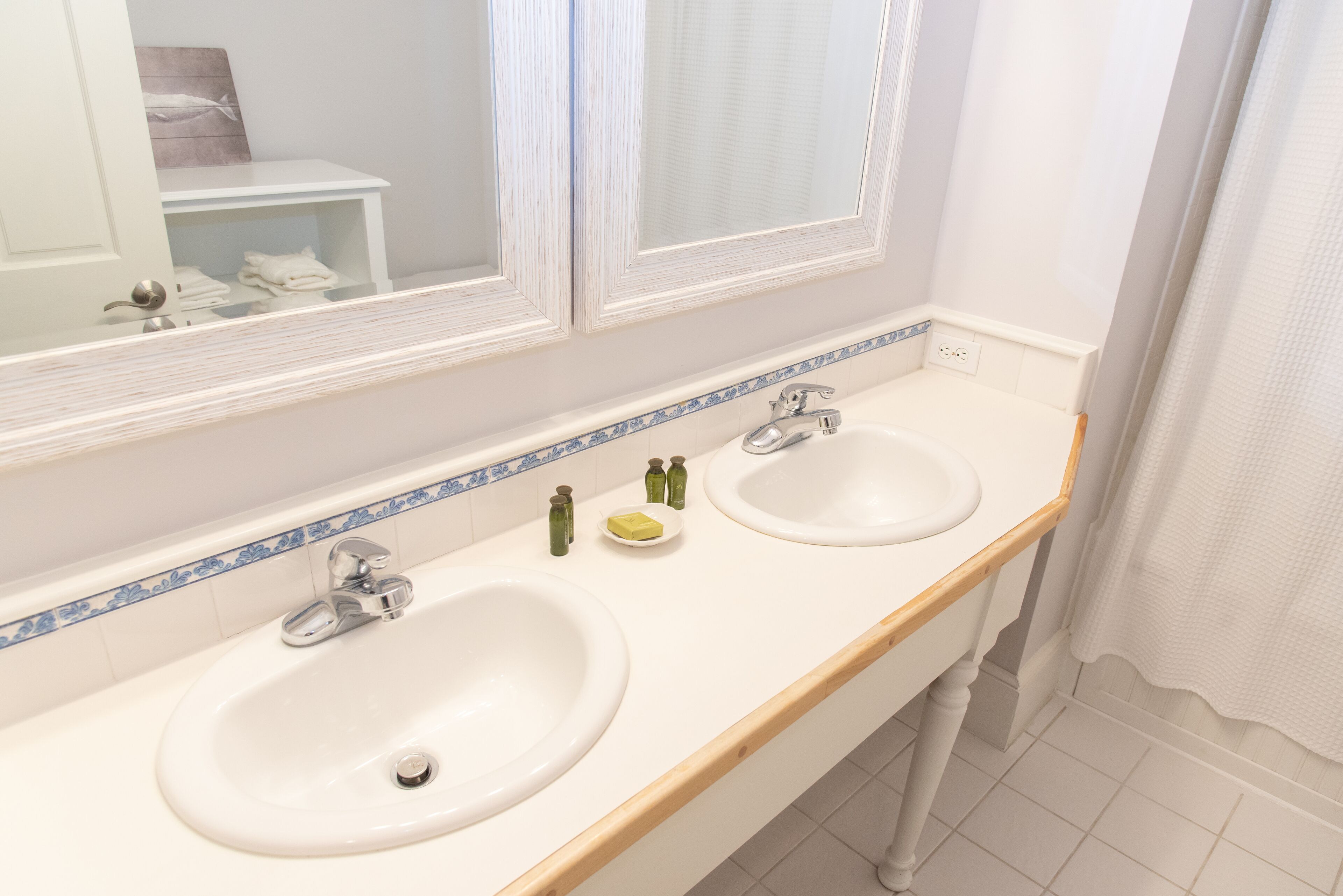 A bathroom with two sinks, a mirror, and a window.