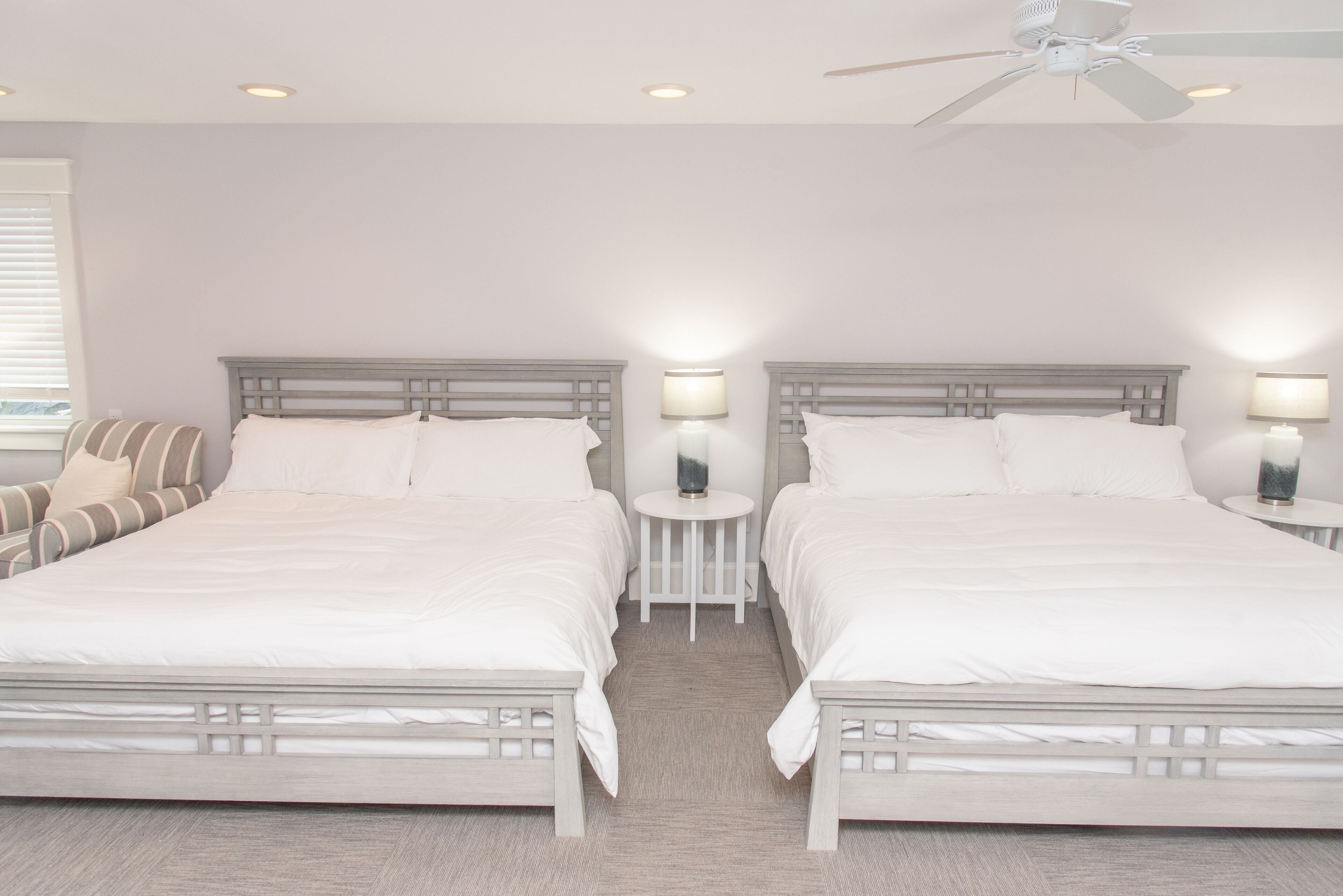 A hotel room with two beds, a ceiling fan, and bedside lamps.