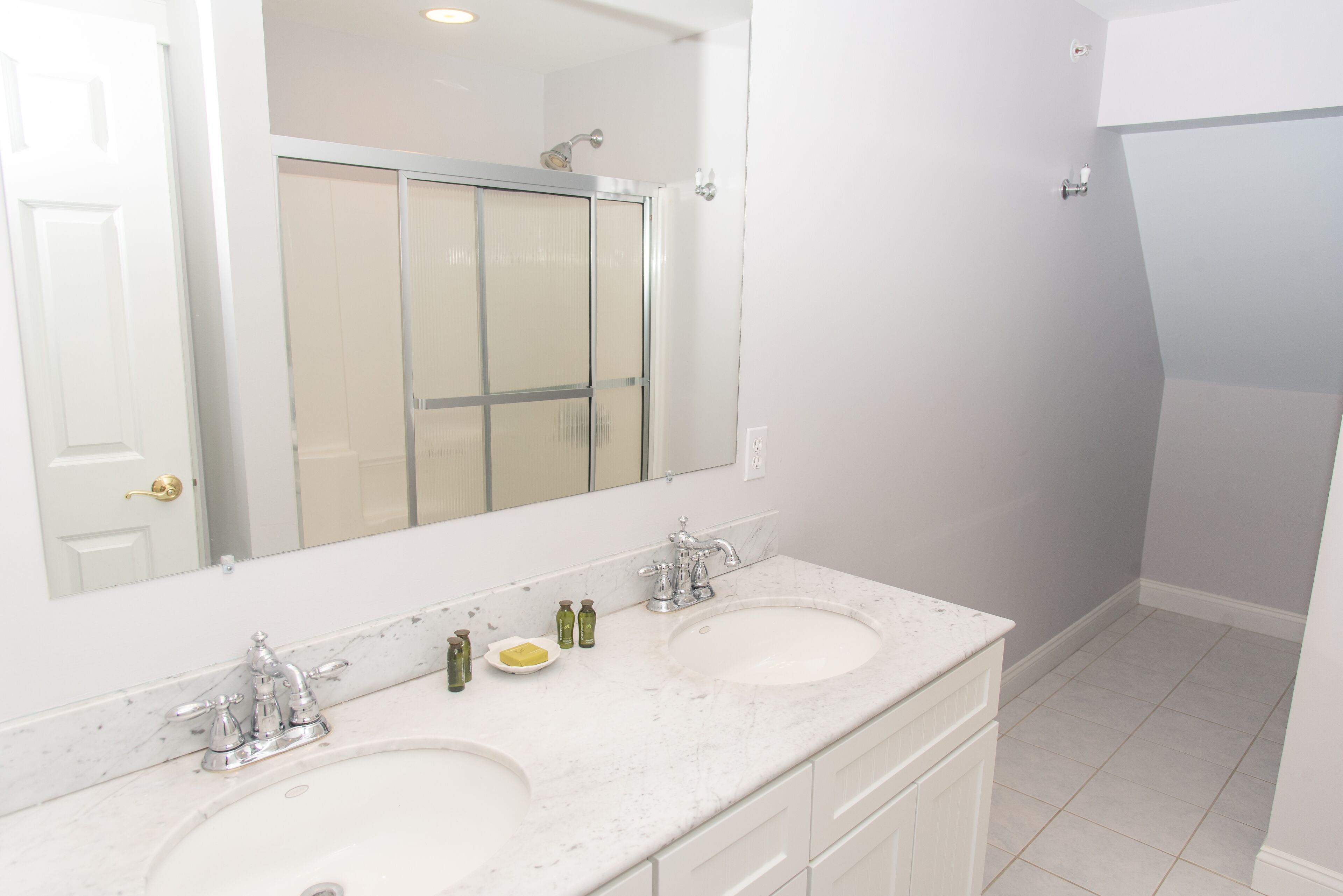 A bathroom with two sinks, a large mirror, and a shower.