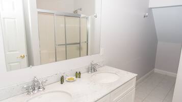 A bathroom with two sinks, a large mirror, and a shower.