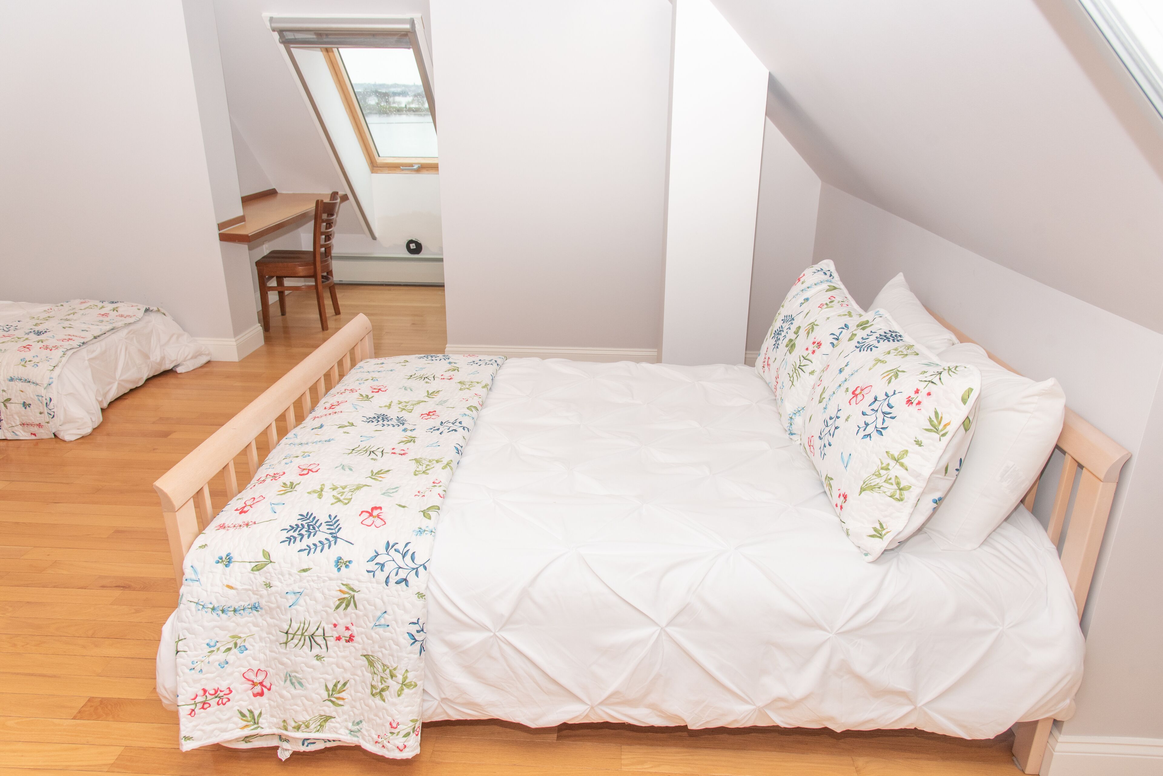A bedroom with a wooden bed, a desk, and a chair.