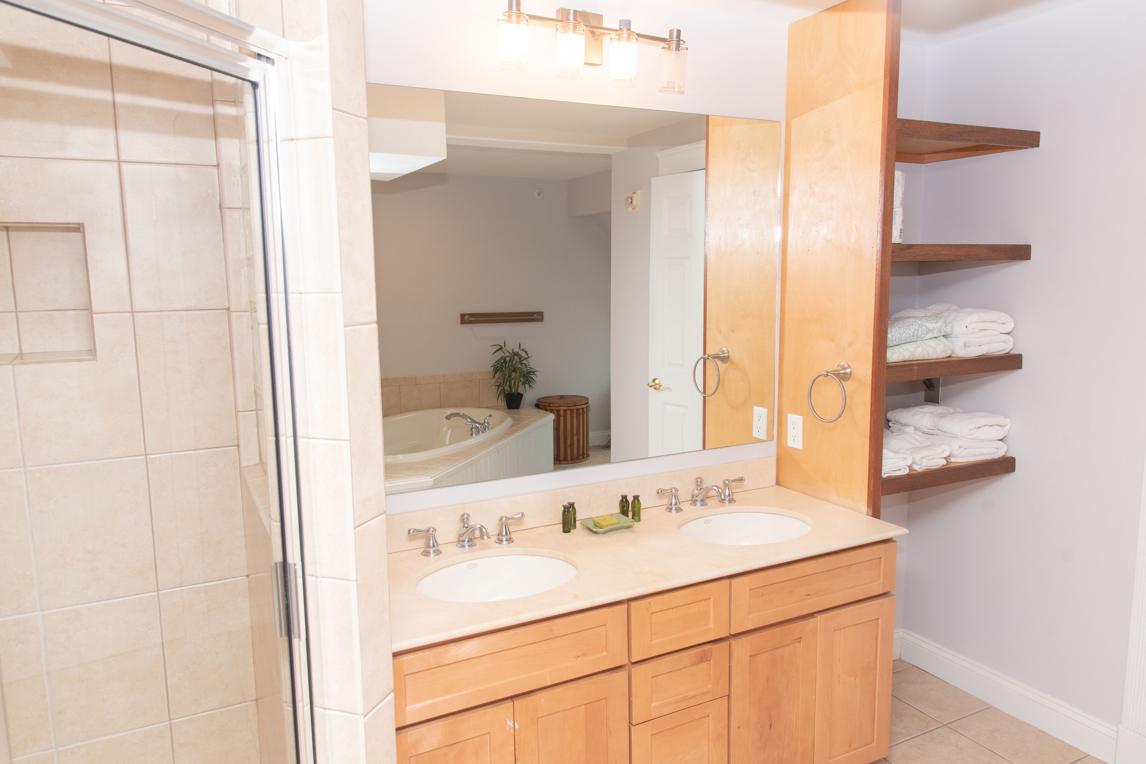 A bathroom with two sinks, a large mirror, and wooden cabinets.