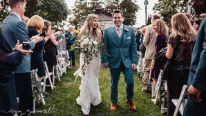 A wedding ceremony with guests seated on white chairs, a bride and groom walking down the aisle, and a grassy outdoor setting. - Inn On Peaks Island (Peaks Island)