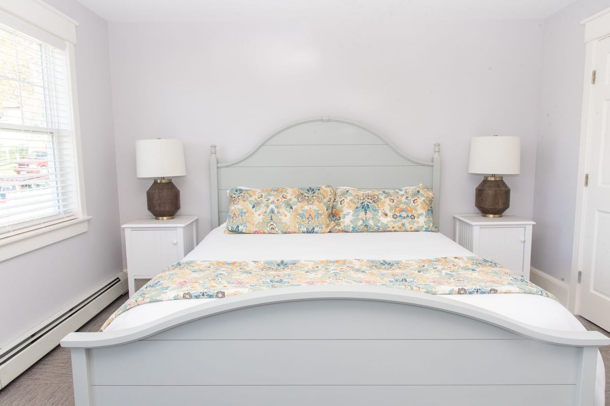 A bed with a curved headboard, two bedside tables with lamps, and a floral bedspread.