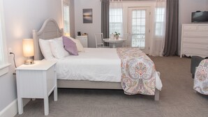 A bedroom with a bed, bedside table, lamp, and a view of the dining area. - Inn On Peaks Island (Peaks Island)