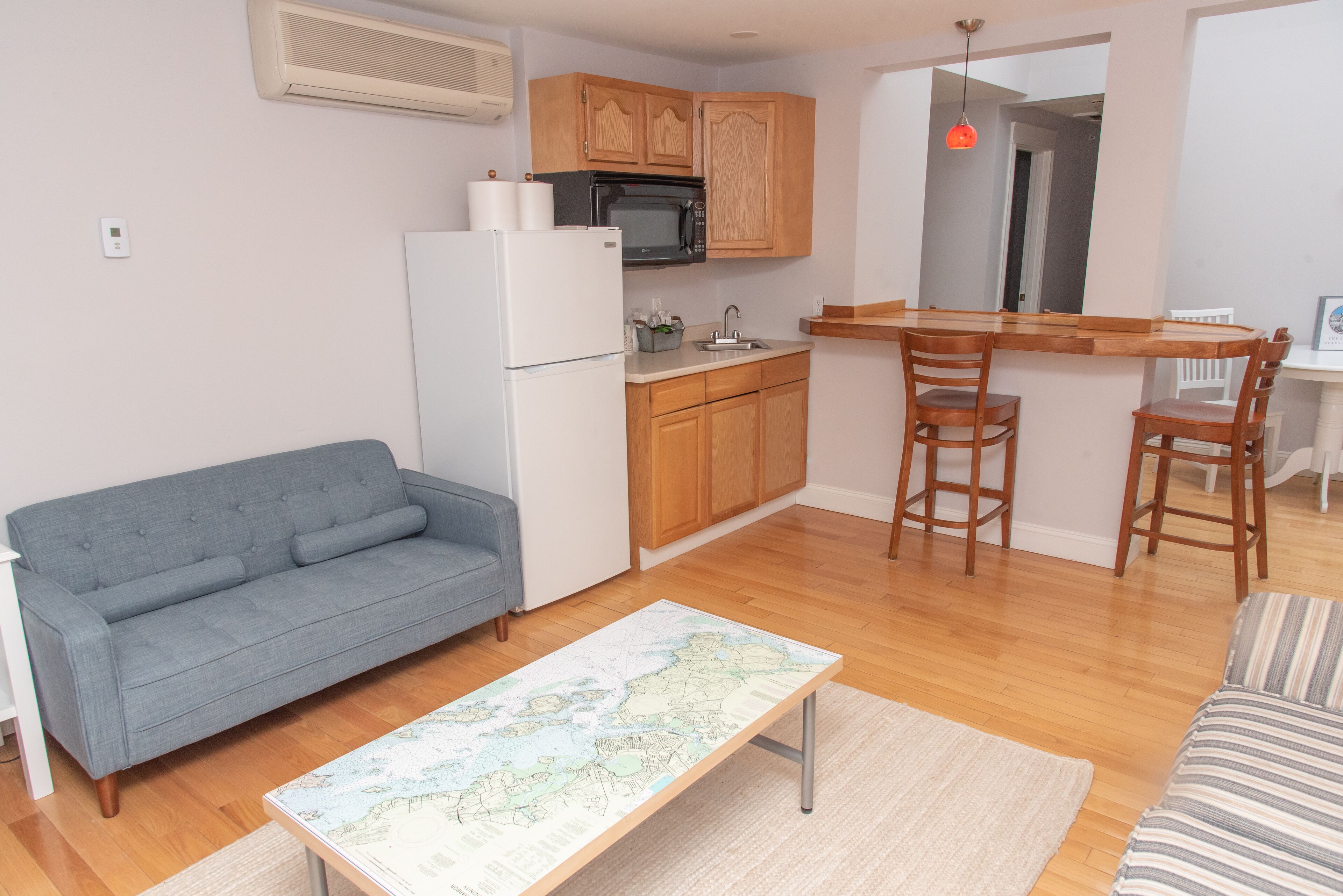 A compact living space with a kitchenette, a sofa, a dining table, and a map table.