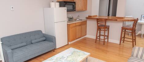 A compact living space with a kitchenette, a sofa, a dining table, and a map table.
