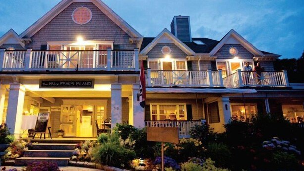 A two-story hotel with a balcony on the second floor, a sign reading "The Inn on Peaks Island," and a flag in front. - Inn On Peaks Island (Peaks Island)