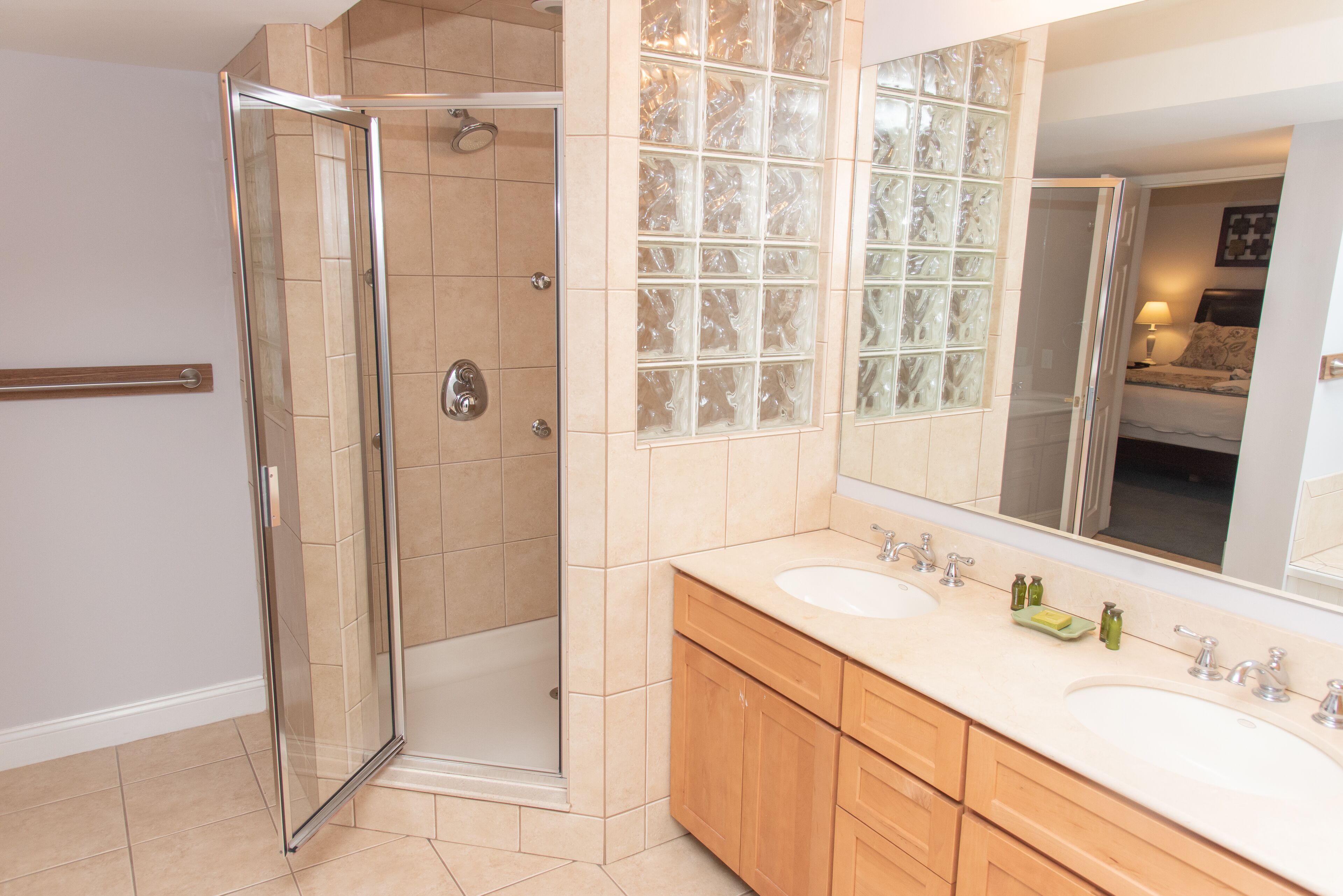 Un bagno moderno con cabina doccia in vetro, lavabo doppio e uno specchio grande.