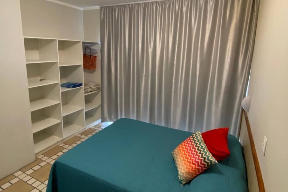 A bedroom with a bed, a wardrobe, and a curtain.