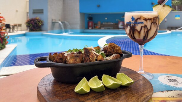 A dining table with a bowl of fried chicken, lime wedges, and a dessert drink. - Hotel Atrium Thermas - Oficial (Caldas Novas)