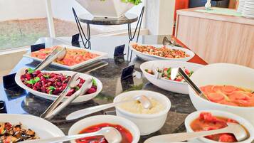 A buffet table with various dishes, including salads, soups, and a fruit bowl.