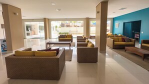 A spacious lobby with multiple seating areas, including sofas and armchairs, arranged around a central coffee table. - Hotel Atrium Thermas - Oficial (Caldas Novas)