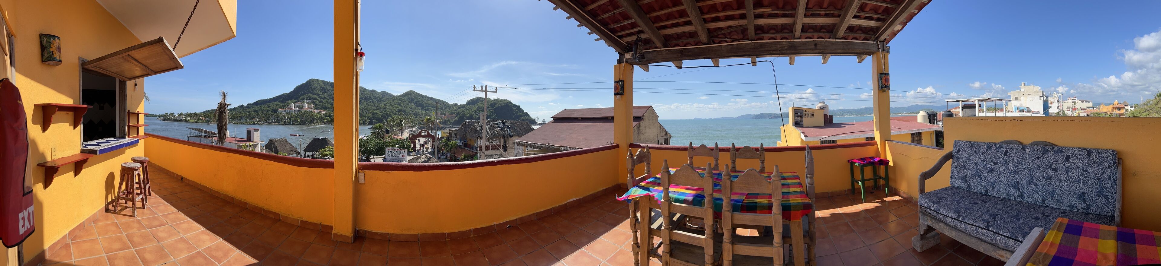 A balcony with a view of a body of water, a chair, a table, and a sofa.