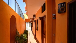 Un couloir étroit aux murs orange, doté d’un sol carrelé et d’une grille métallique au bout.