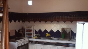 Una cocina con armarios blancos, estufa, pileta y salpicadero de azulejos.