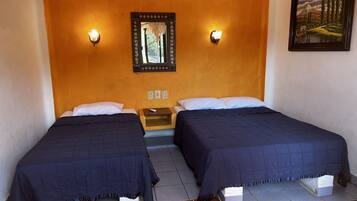 A room with two beds, a nightstand, a wall-mounted mirror, and a painting.