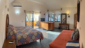 Une chambre d’hôtel avec un lit, un canapé, un bureau et une vue sur l’extérieur.
