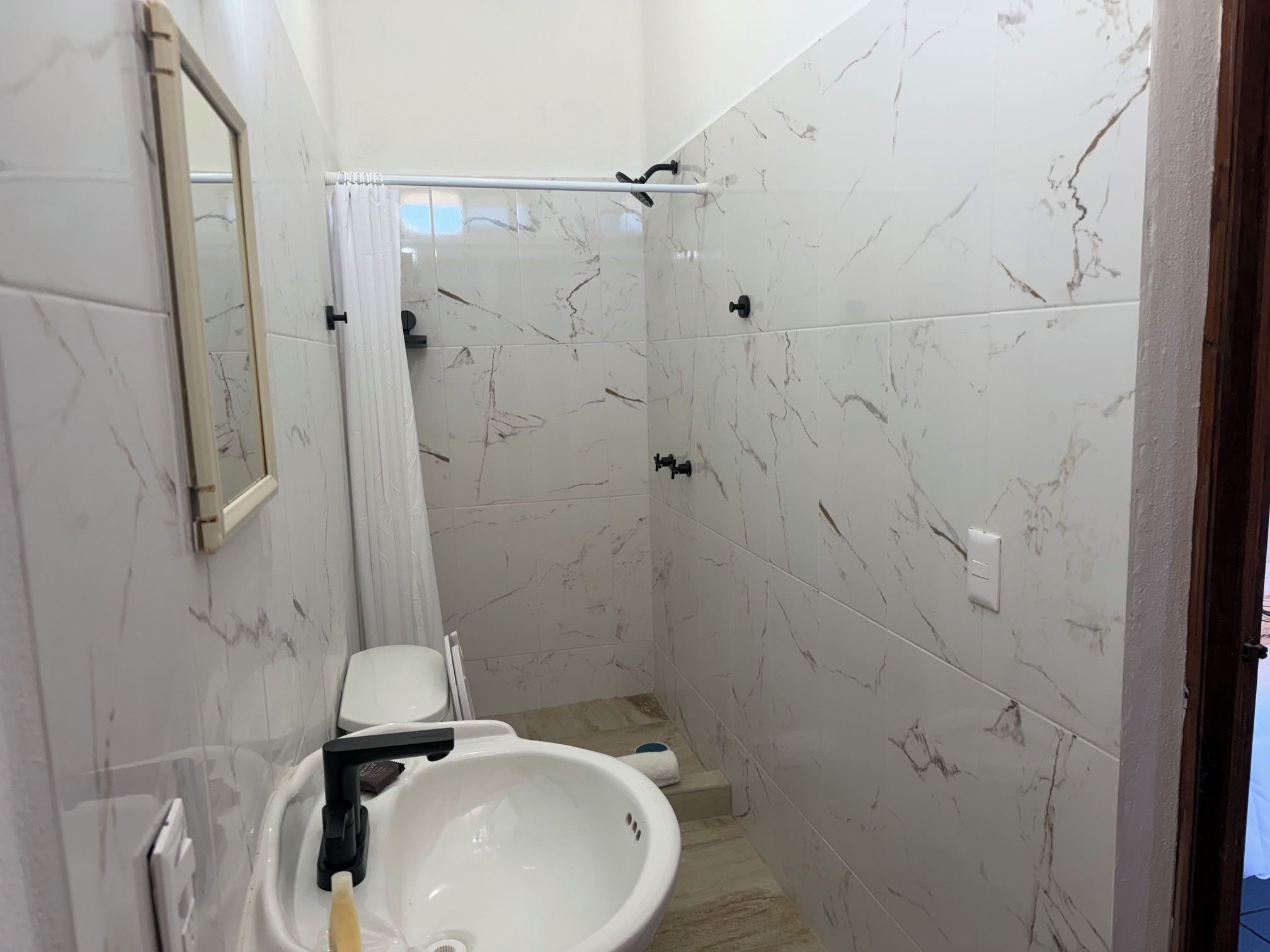 A bathroom with a white sink, a mirror, and a shower area with a curtain.