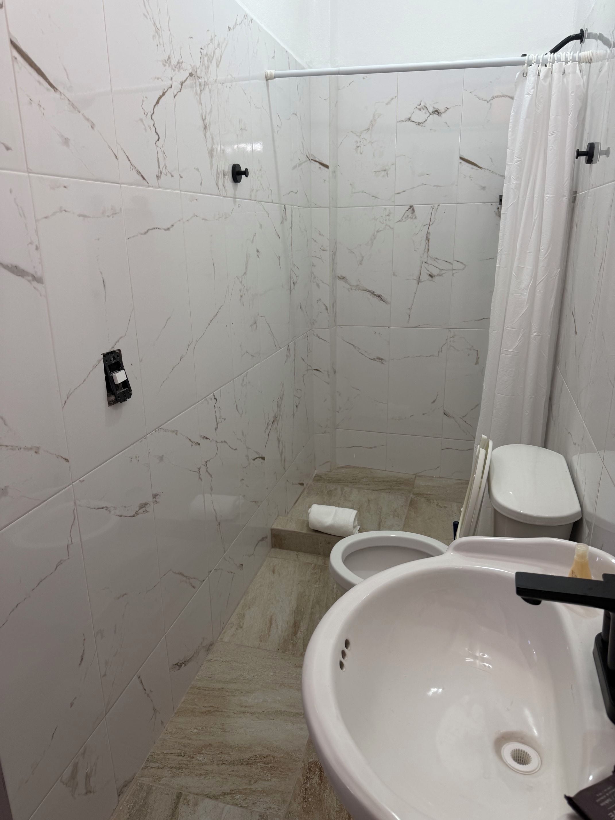 A bathroom with a white sink, toilet, and shower curtain.