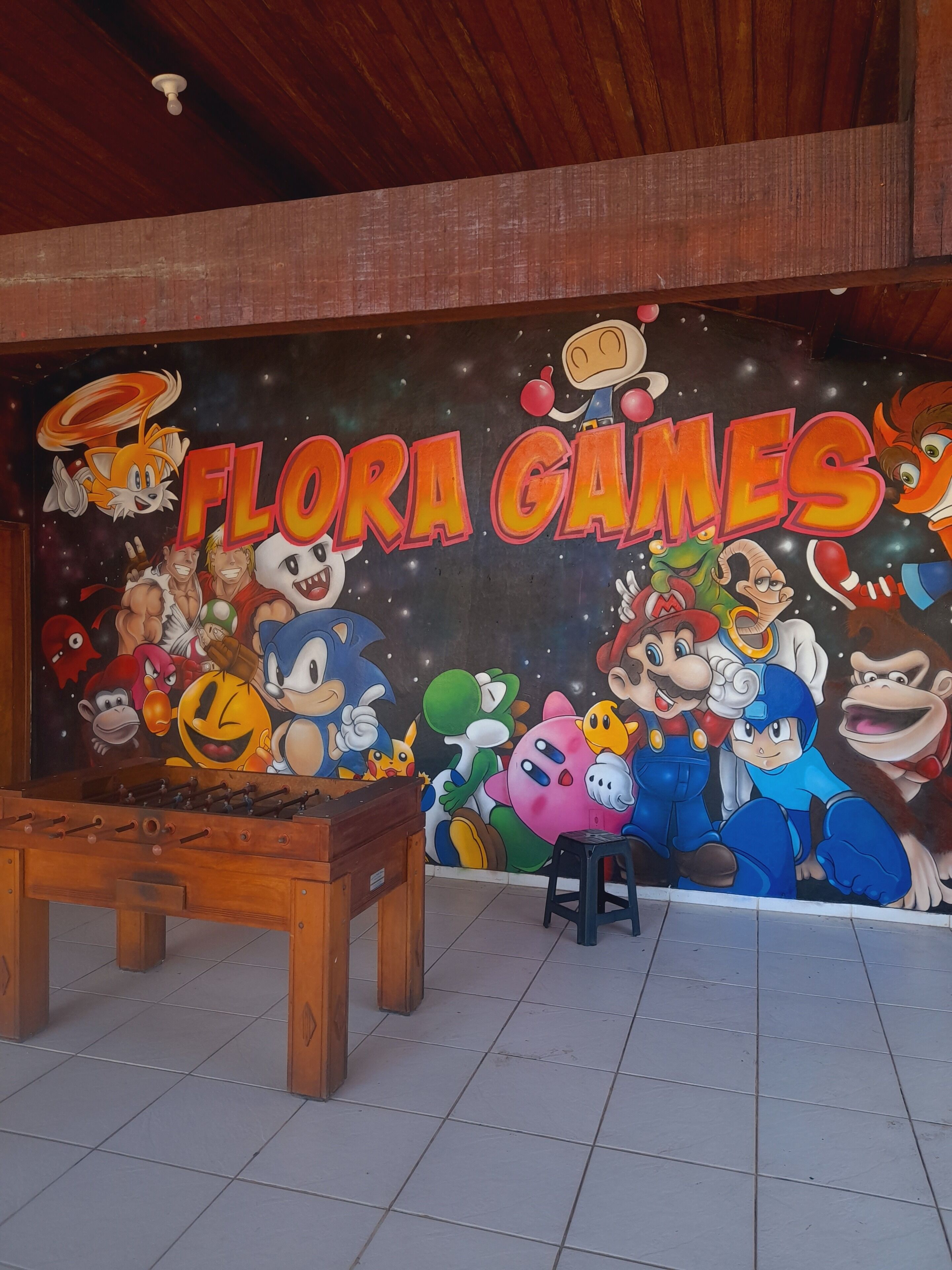 A room with a mural of various video game characters and the text "FLORA GAMES".
