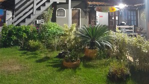 A two-story building with a covered patio area, a staircase, and a garden with potted plants. - Pousada Flora Búzios (Búzios)