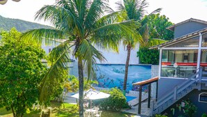 A tropical resort with a pool, palm trees, and a mural of sea creatures on the building. - Pousada Flora Búzios (Búzios)