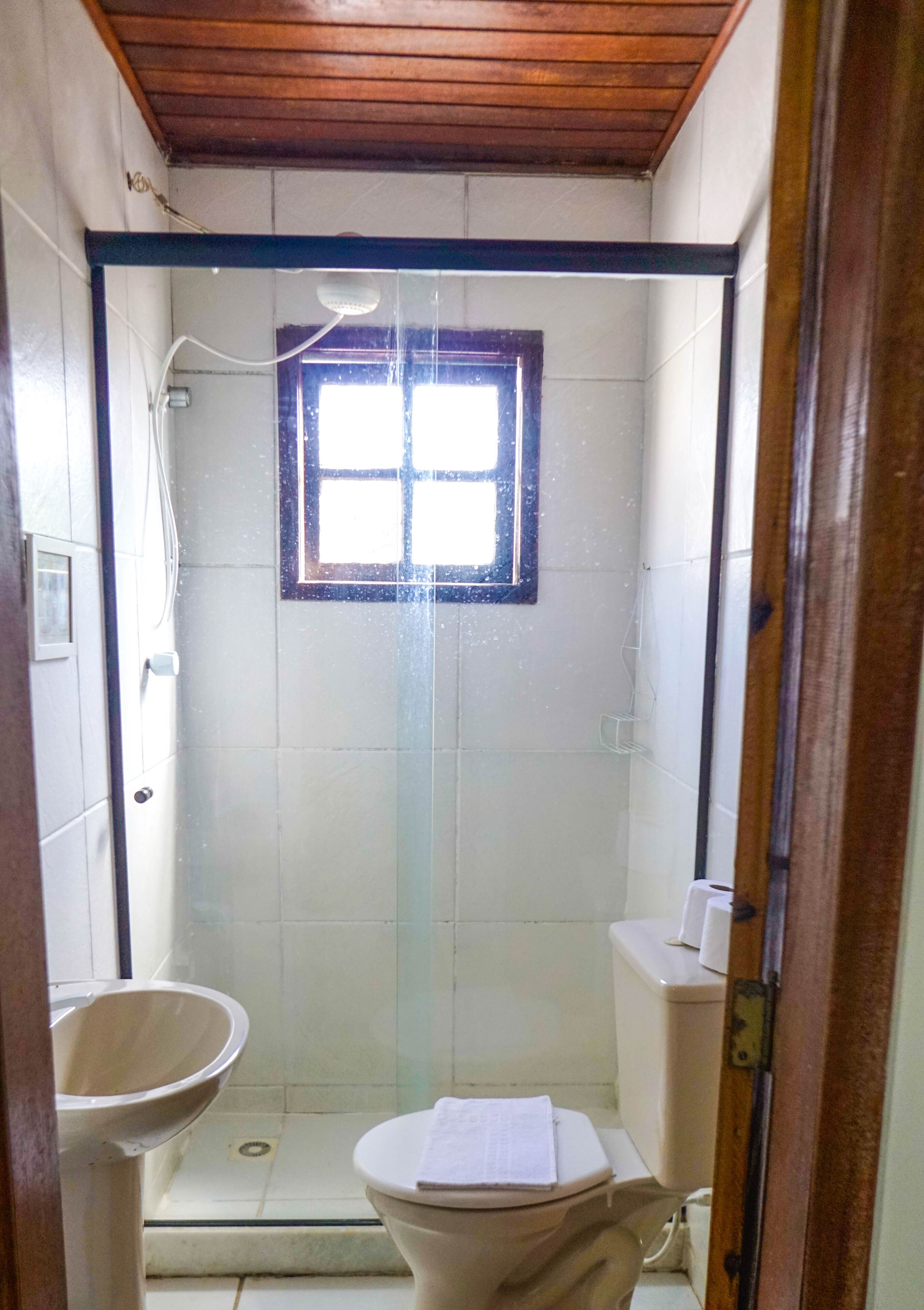 Un baño pequeño y cerrado con ventana, inodoro y lavabo.