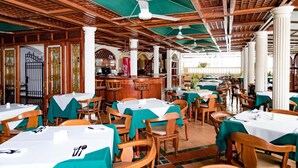 A restaurant with wooden ceiling beams, green umbrellas, and white columns. Tables are set with white tablecloths and wooden chairs. - Ayenda 1408 Jaba Santiago de Cali (Cali)